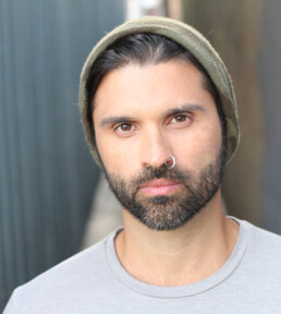 Man with beard, nose ring, and beanie looking at camera