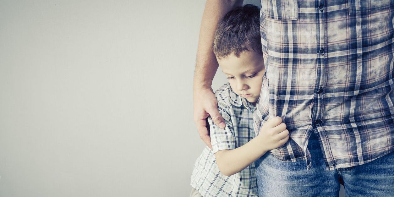 young boy holding onto father to show how addiction impacts families