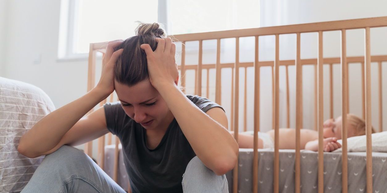 woman depressed next to baby in crib